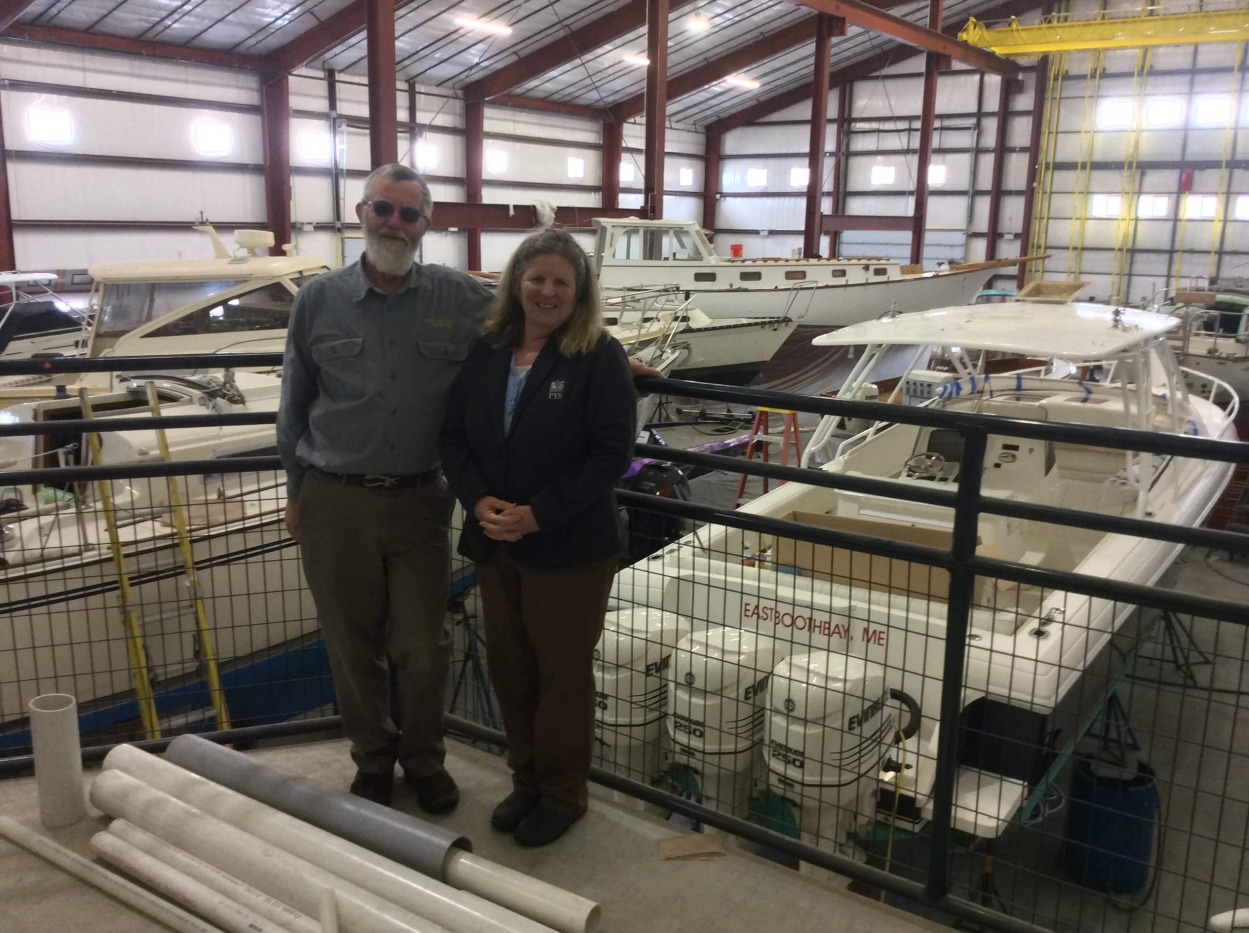 Man and woman in front of boats in inside storage facility