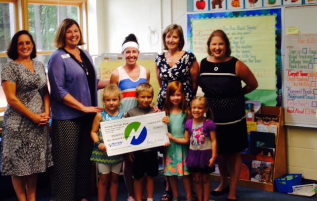 NSB employee presents donation check to a group of Memorial School staff members and students