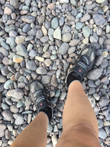Feet in bike shoes on a rocky surface
