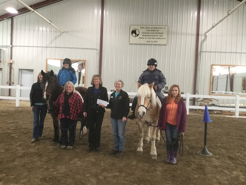 Group of people and horses at a check presentation.