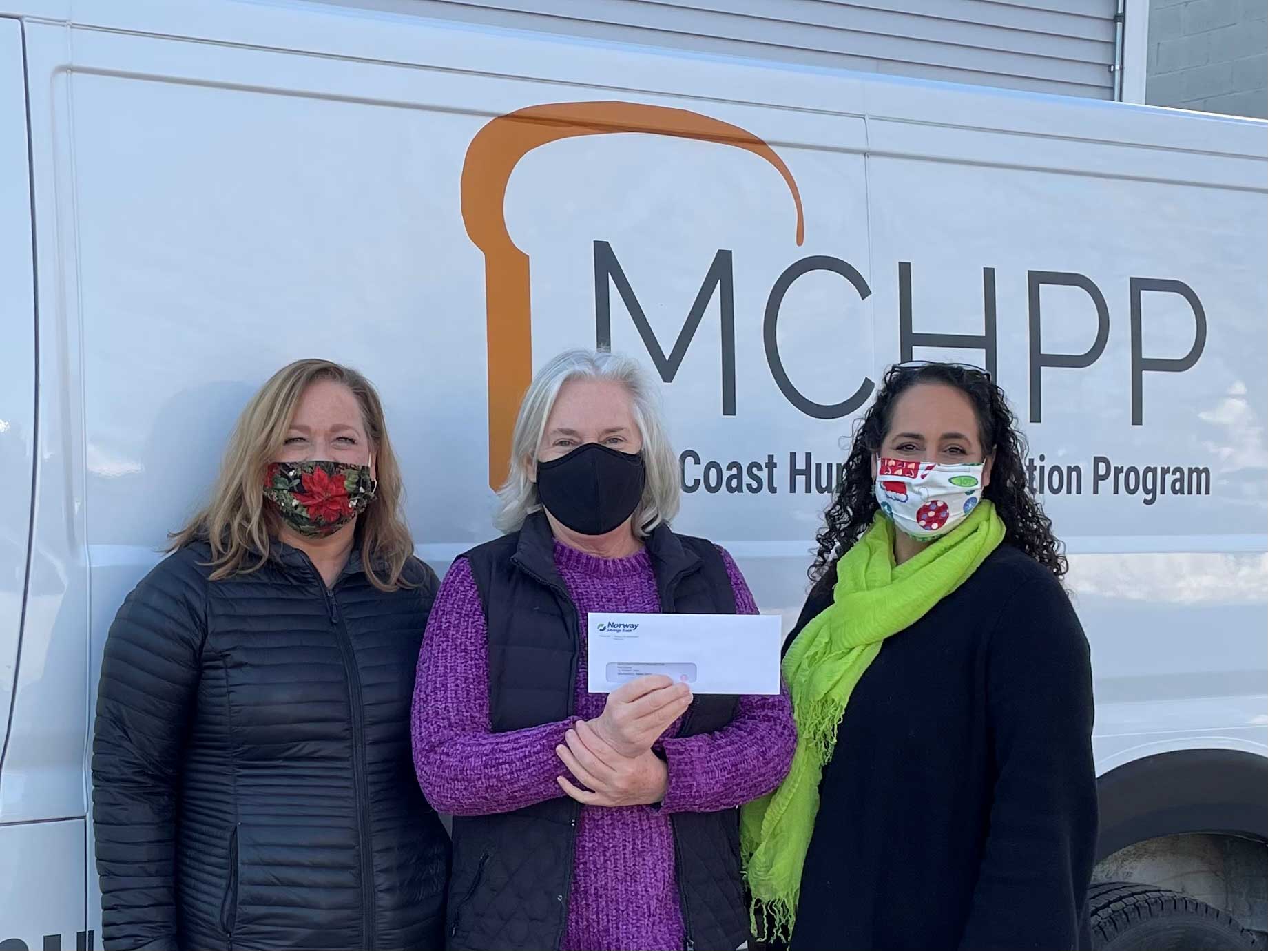 Three women - two are presenting a check while the third receives the check