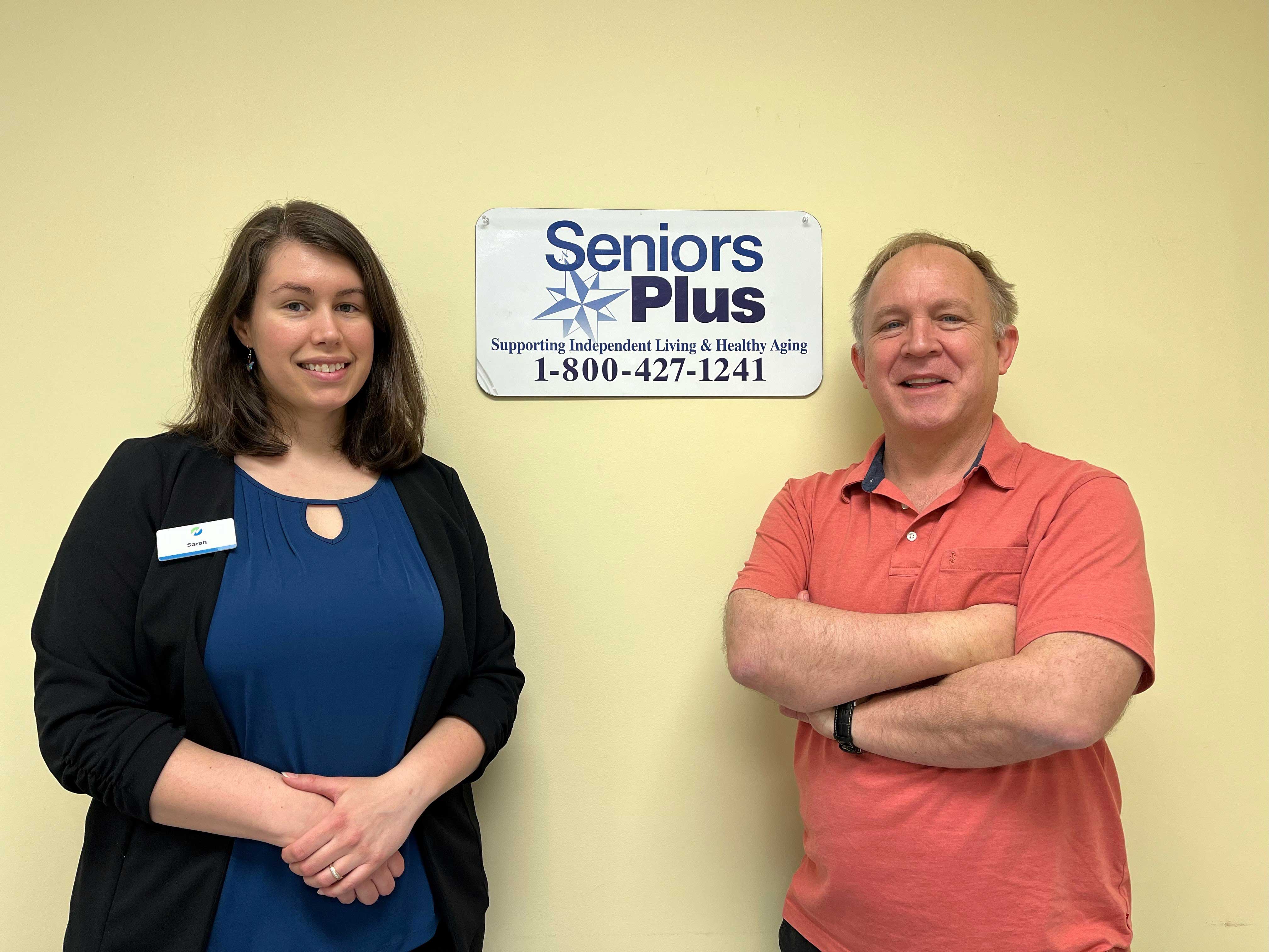 A man and woman standing in front of SeniorsPlus sign