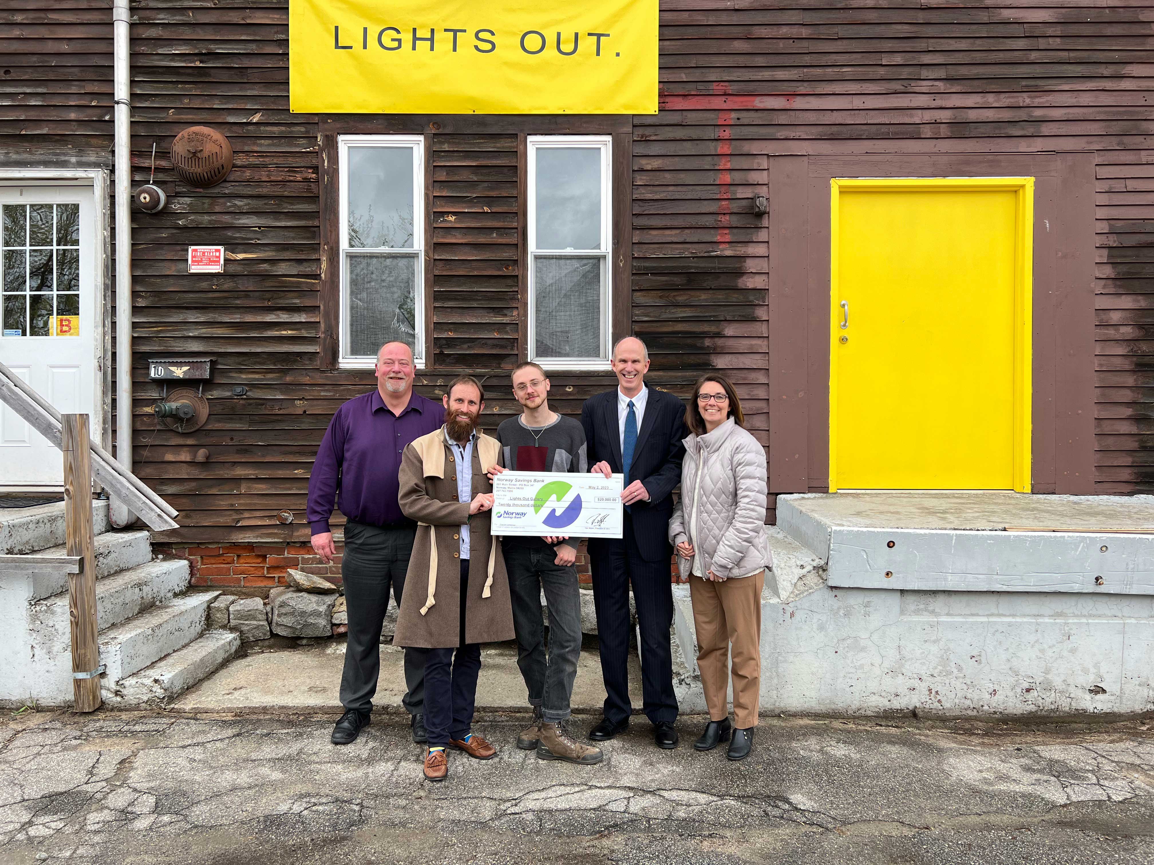 Norway Savings Bank employees presenting a large check to Lights Out Gallery