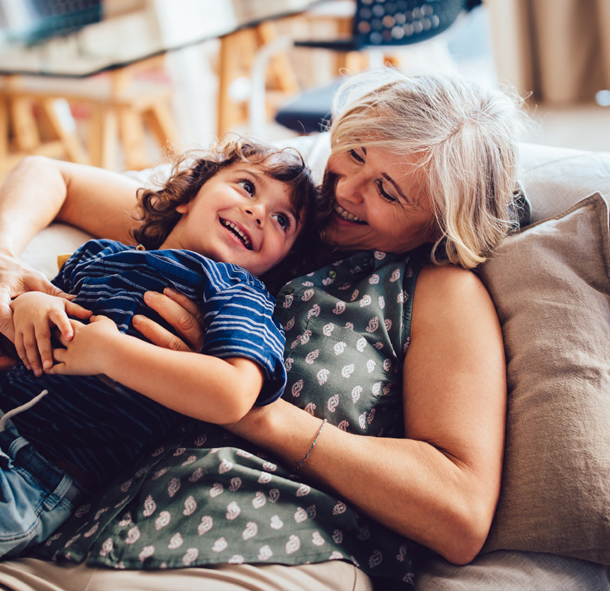 Woman sitting on a couch hugging her grandson and happy to use asset management group services at norway savings