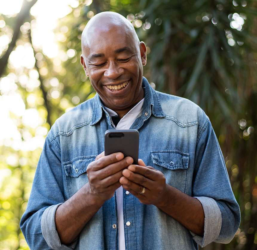 Man smiling and looking into his phone happy to use asset management group services at norway savings
