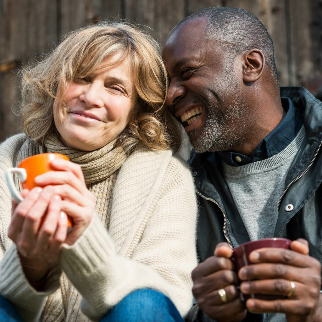 Husband and wife drinking coffee and smiling because they use investment and trust services