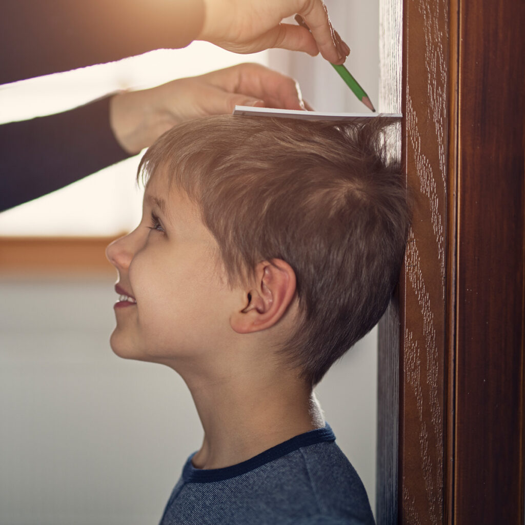 boy having his height marked on the wall of his house