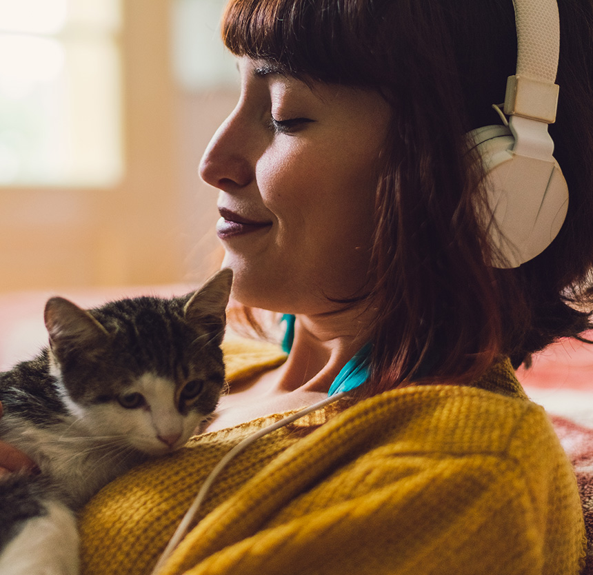 woman holding a cat listening to headphones smiling because of personal banking at norway savings