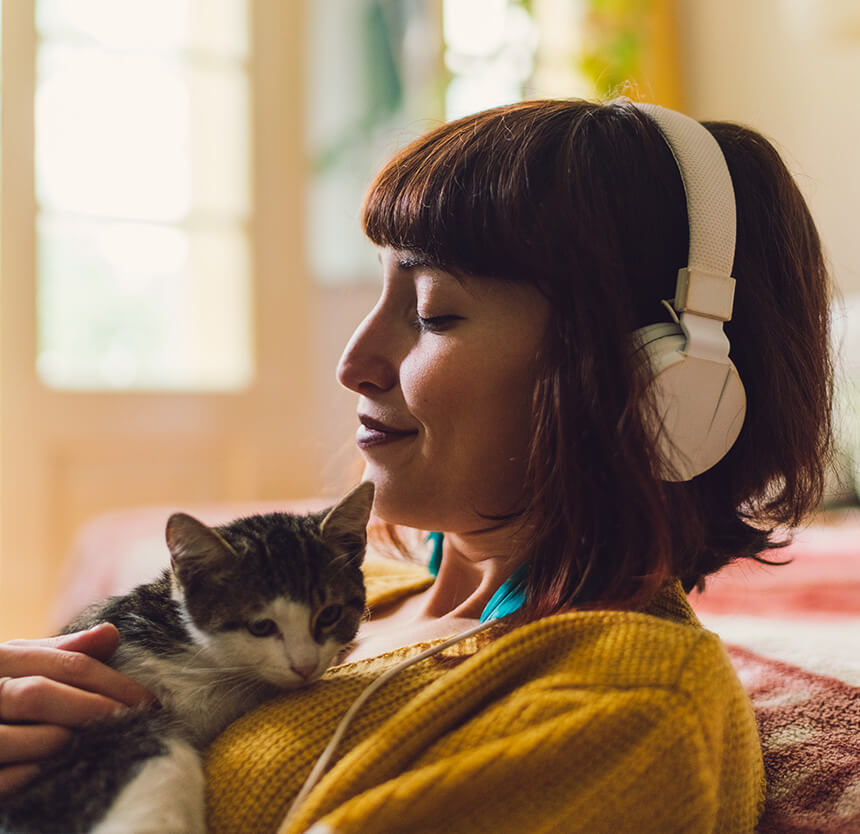 woman holding a cat listening to headphones smiling because of personal banking at norway savings