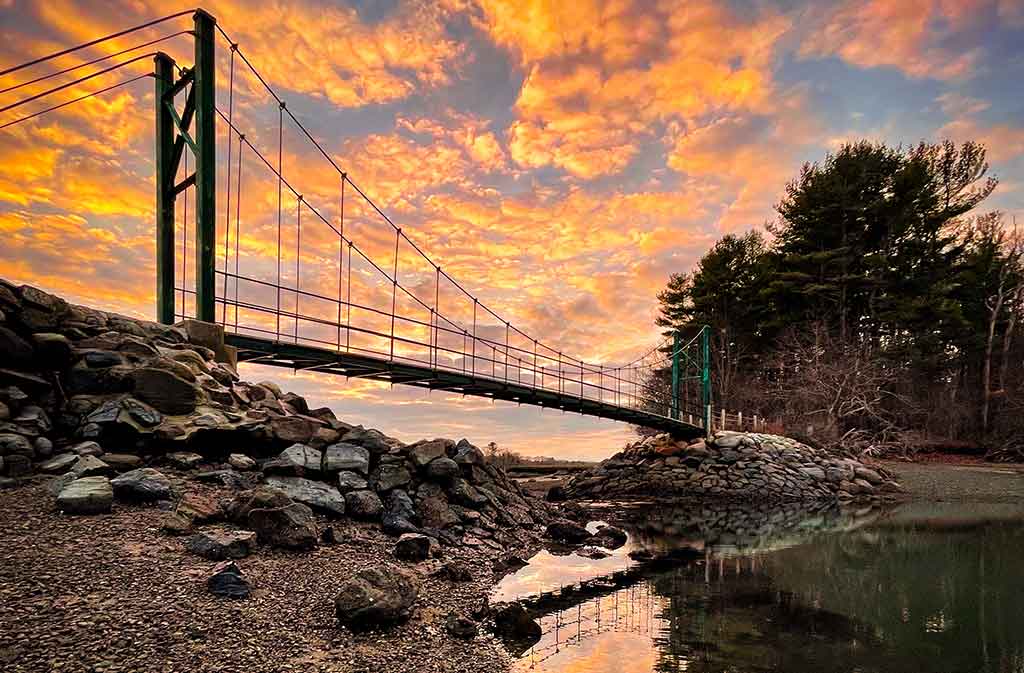 Sun setting over wire bridge